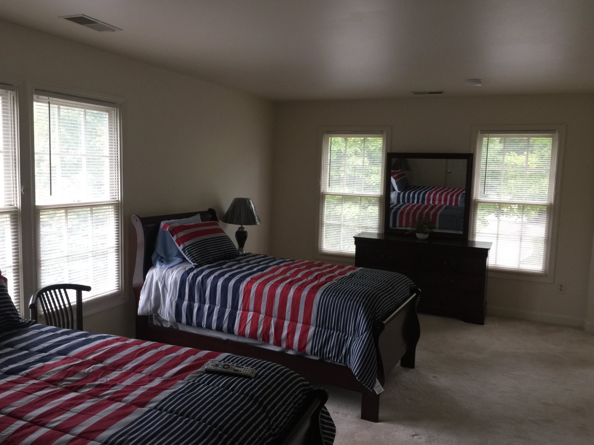 A bedroom with two twin beds featuring striped bedding and a dresser with a mirror.