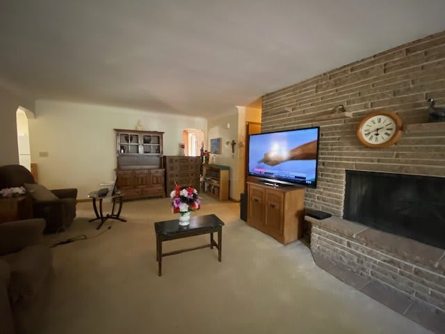A cozy living room with a brick fireplace, television, and classic furniture.