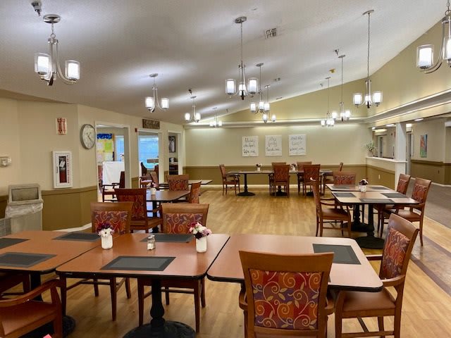An empty dining room with neatly arranged tables and chairs, featuring a warm and inviting interior design.