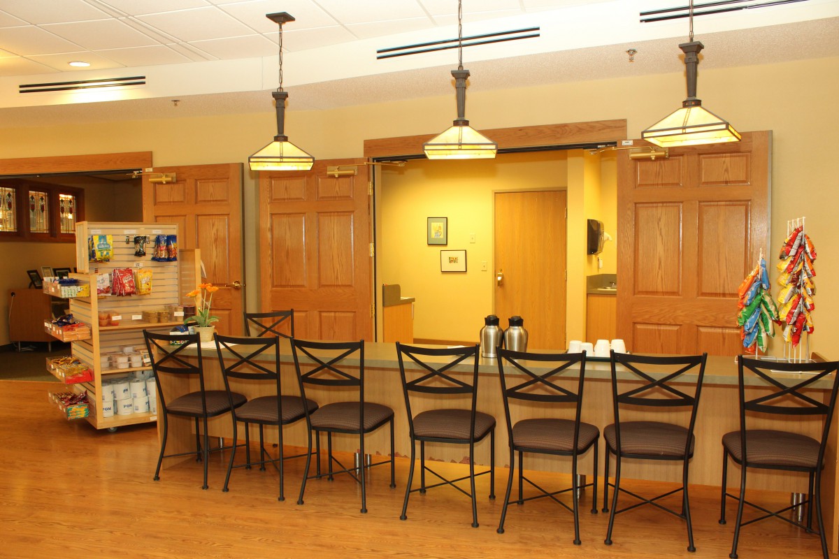 A well-lit kitchen area with a row of bar stools and pendant lighting above the countertop.