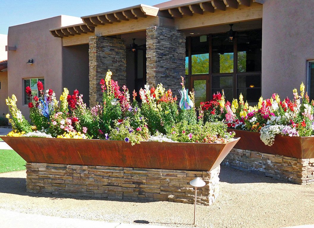A vibrant garden with colorful flowers in front of a modern stone building.