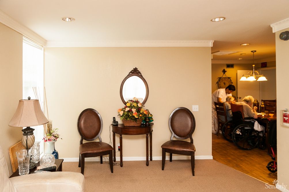 A cozy living room setup with two chairs, a small table, and an oval mirror on the wall.