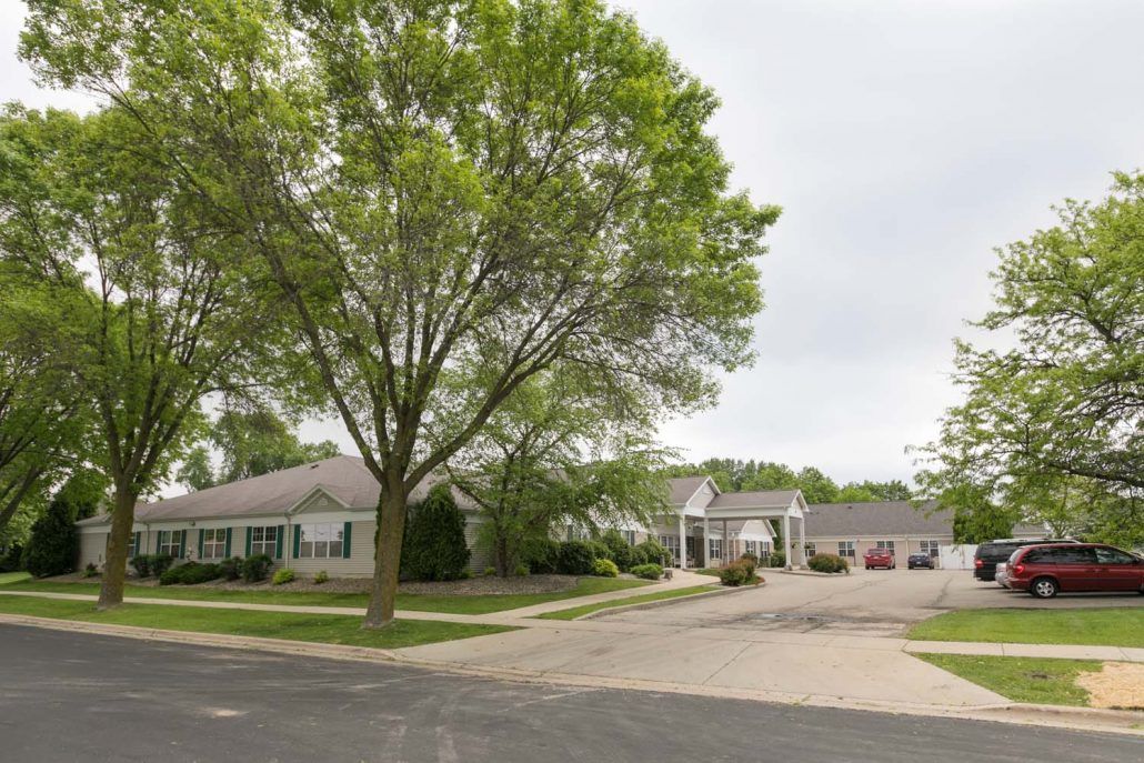 A quiet suburban neighborhood with houses and lush green trees lining the street.