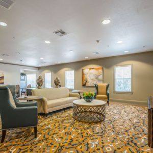 A cozy living room with sofas, chairs, decorative carpet, and artwork on the walls.