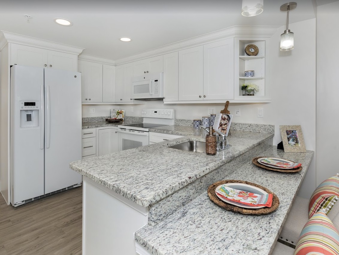 A modern kitchen featuring white cabinets and granite countertops.