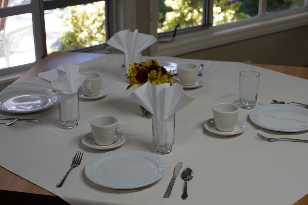 A dining table set with plates, cups, cutlery, and decorated with flowers.