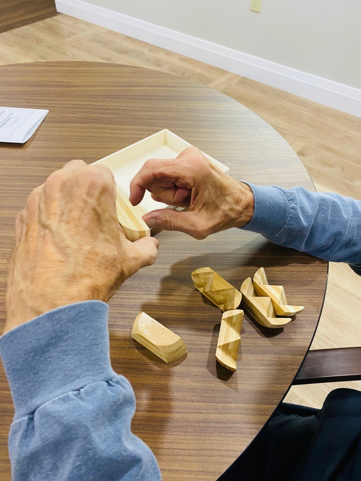 A person assembling wooden blocks on a table.