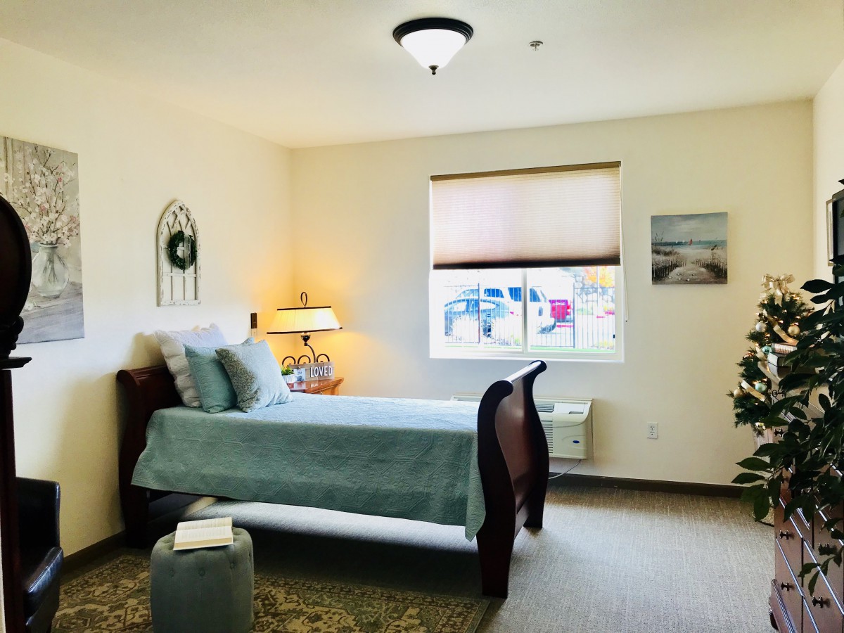 A cozy bedroom with a neatly made bed, decorative elements, and a window view.