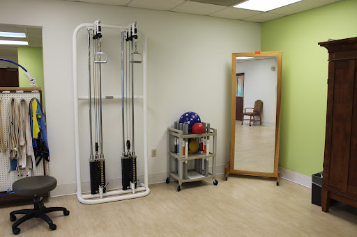 A rehabilitation room featuring exercise equipment and a mirror.