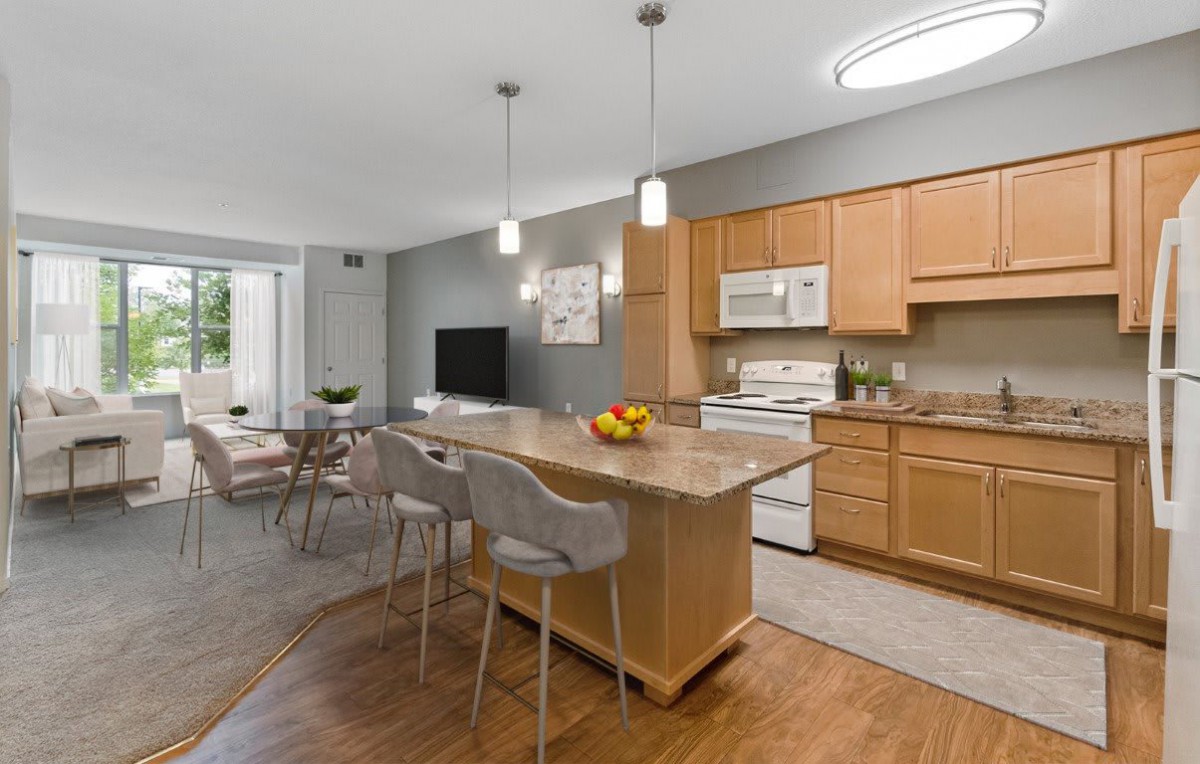 A modern kitchen with an open dining area, featuring a central island and pendant lights.