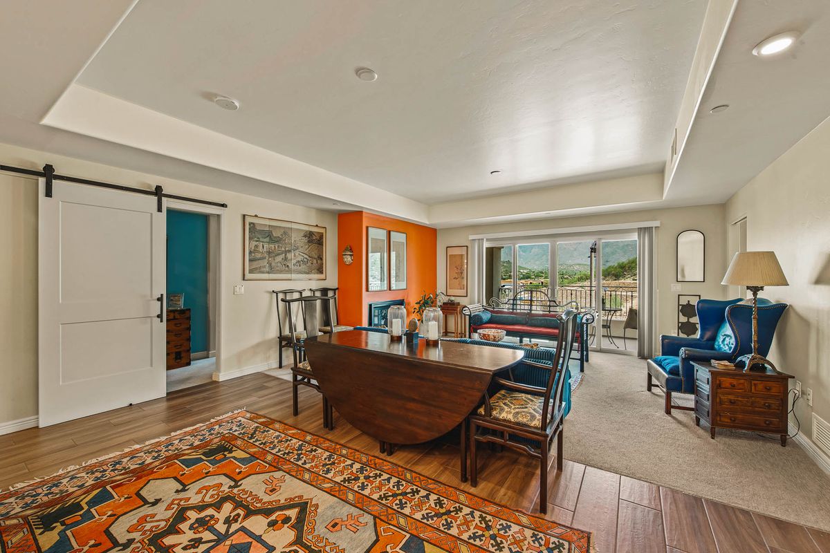 A spacious and well-lit living room featuring vibrant decor, hardwood flooring, and large windows overlooking a scenic view.