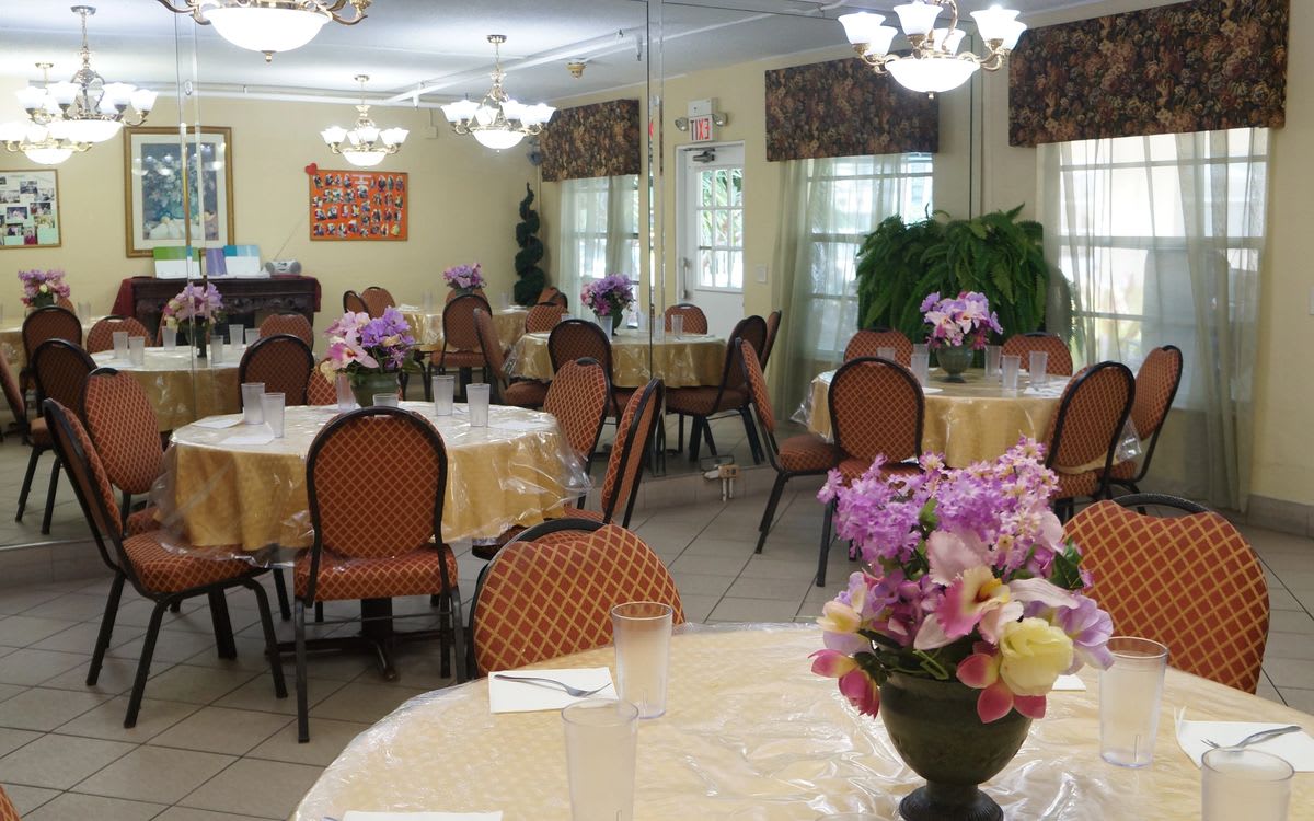 A well-decorated dining area with round tables, chairs, and floral centerpieces.