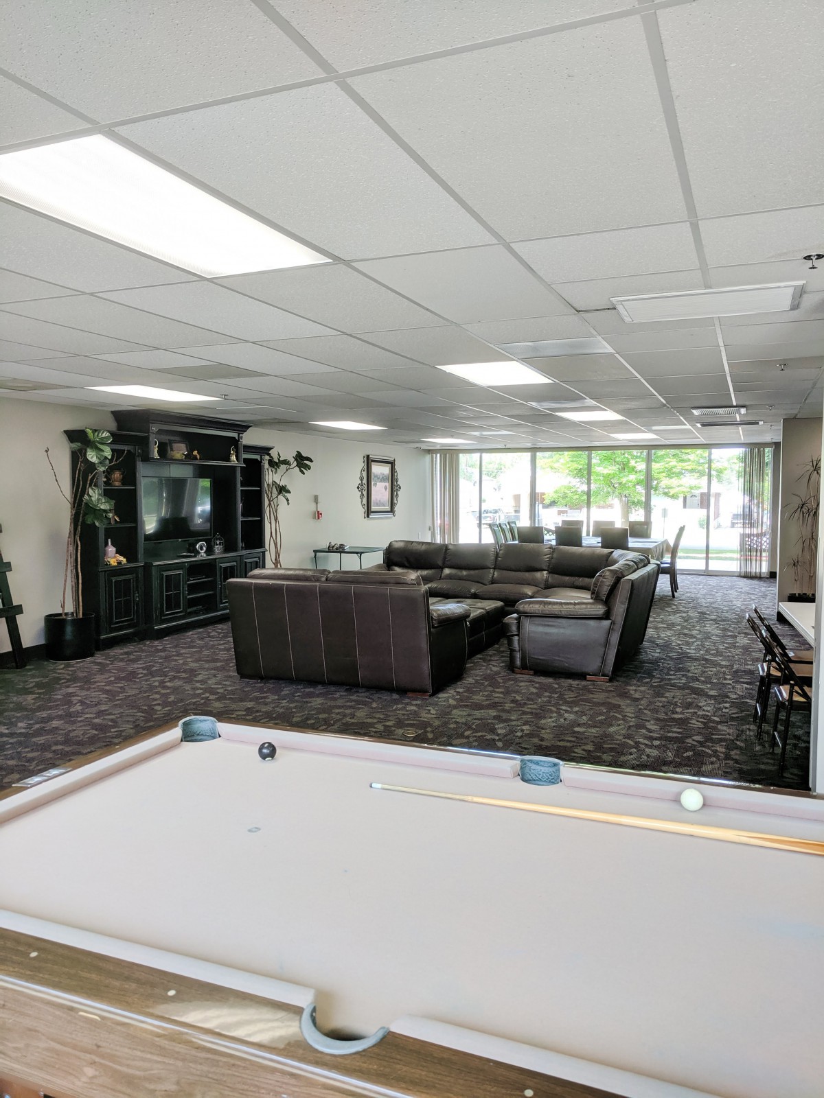 A spacious lounge area featuring a pool table, cozy couches, and a large television.