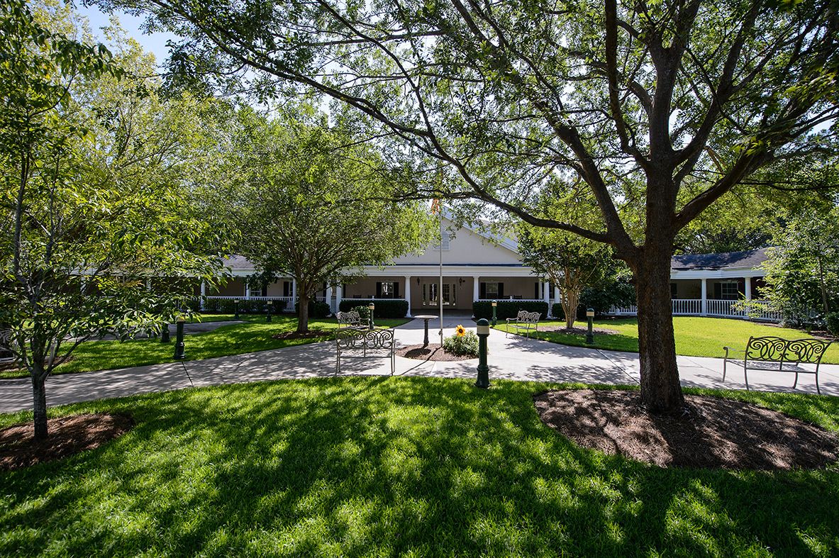 A picturesque house with a lush green yard and mature trees.
