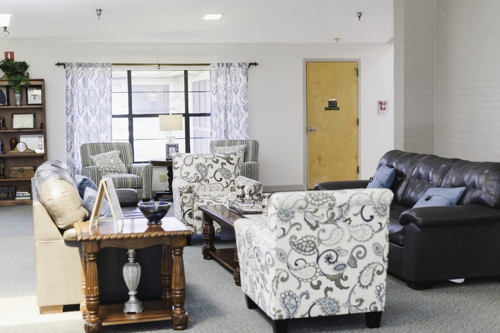 A cozy living room with patterned chairs, sofas, and a wooden table.