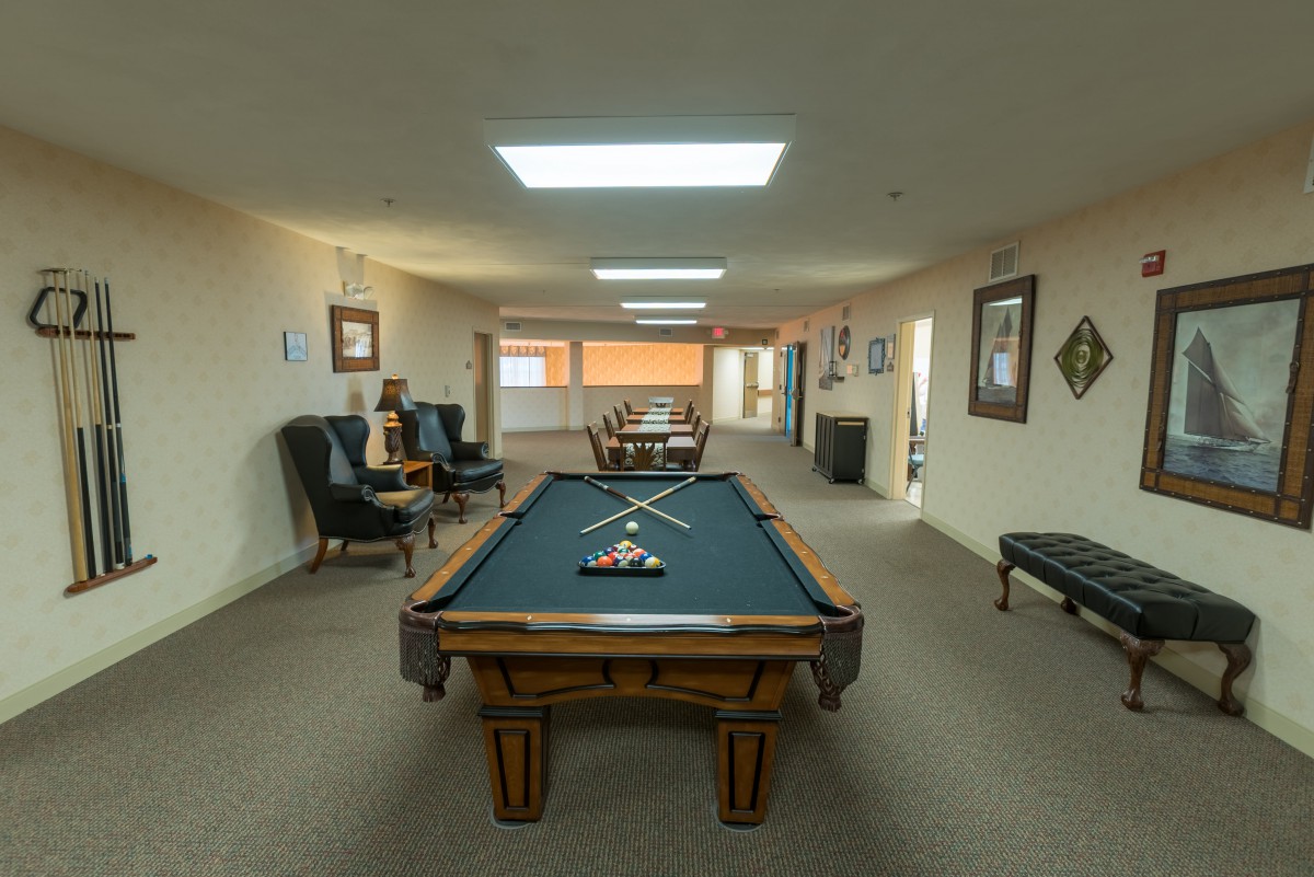 A spacious game room featuring a pool table, with chairs and artwork adorning the walls.