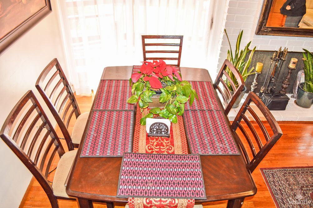 A dining table elegantly set with patterned placemats and a plant centerpiece.