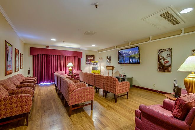 A cozy living room with a row of armchairs, a wall-mounted television, and wooden flooring.