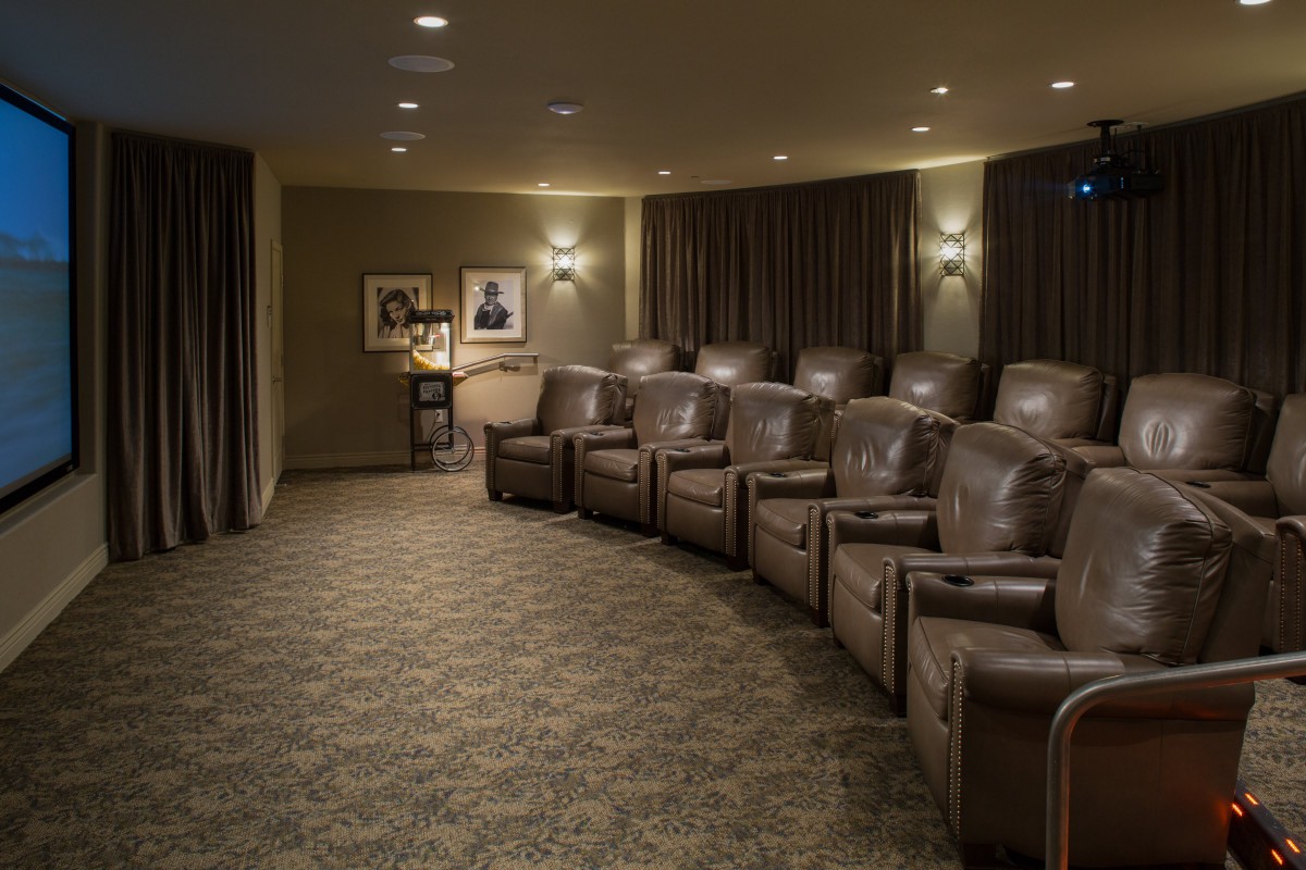 A cozy home theater with a row of leather recliner chairs and dim ambient lighting.