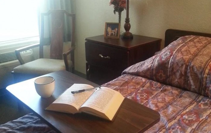 A cozy bedroom setting with a book and cup on the bedside table.