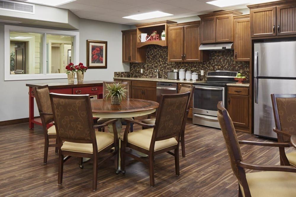 A modern kitchen and dining area with wooden cabinets, a round table, and comfortable chairs.