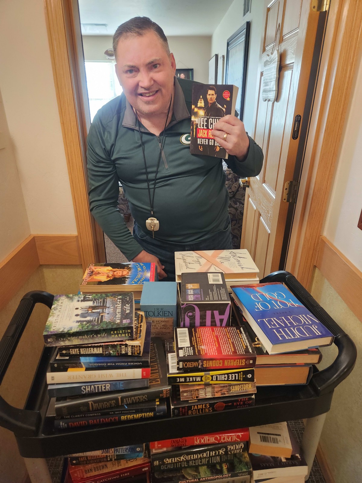 A person standing with a cart full of books indoors.