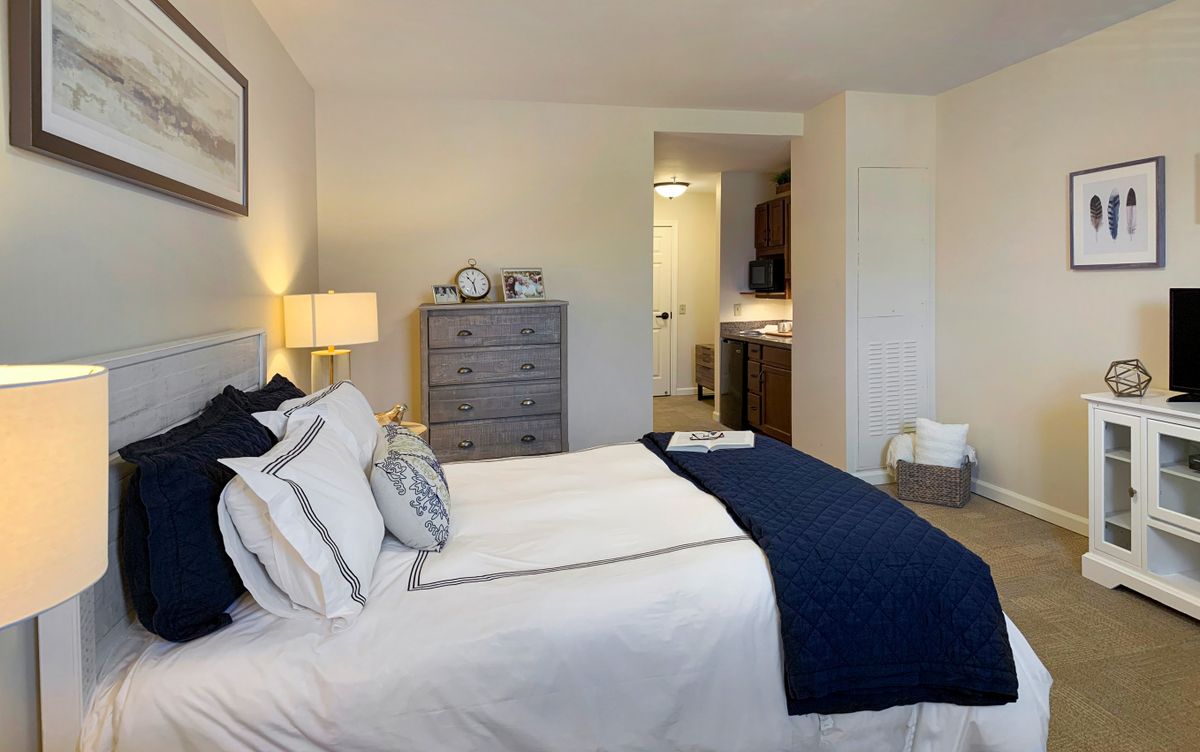 Modern bedroom with crisp white and navy accents, featuring a cozy bed and stylish decor.