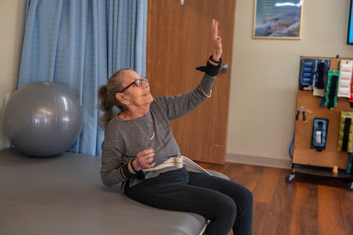 An elderly woman participates in a physical therapy session, demonstrating her commitment to rehabilitation and wellness.