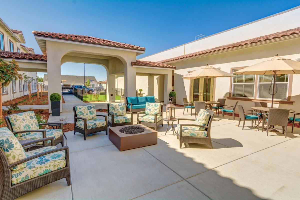 A sunny outdoor patio with furniture and a fire pit.