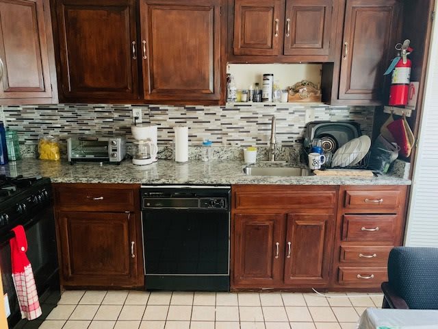 A kitchen featuring wooden cabinets, a tiled backsplash, and various appliances on the countertop.