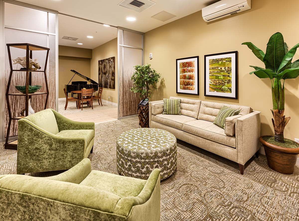A cozy living room with elegant furniture and a grand piano in the background.