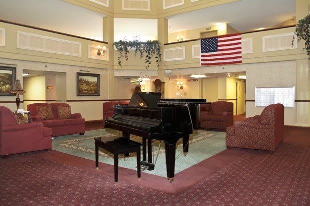 A grand piano in a hotel lobby with seating and an American flag.