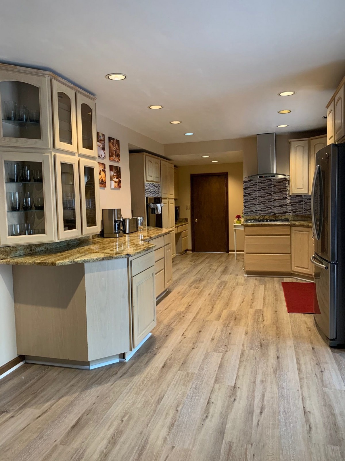 A modern kitchen with wood flooring, sleek cabinets, and contemporary appliances.