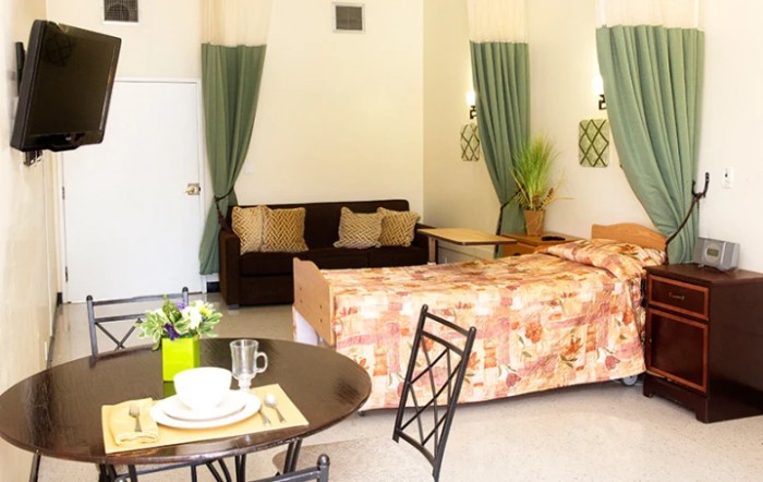 A cozy hotel room with a bed, sofa, and dining area.