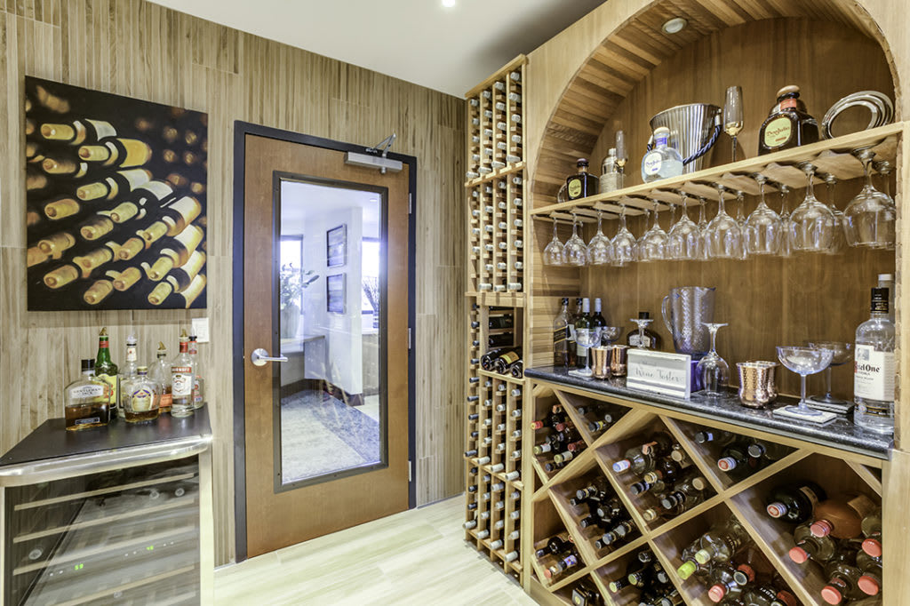 A stylish wine cellar with wooden shelves filled with bottles and glasses.