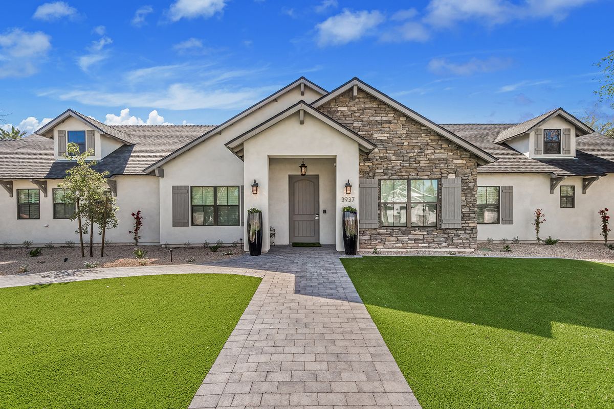 A modern suburban house with a neatly landscaped front yard and stone detailing.