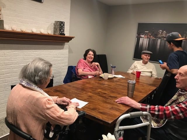 A group of seniors sitting around a wooden table engaged in conversation.