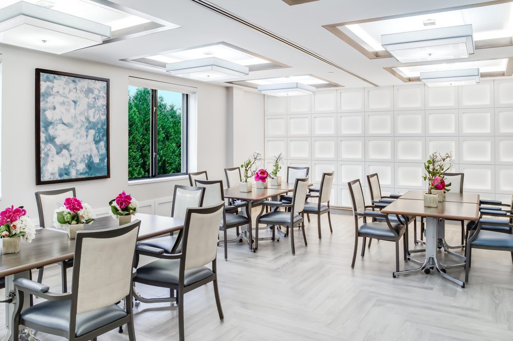 A modern and elegantly decorated dining area with tables and chairs, accented by floral centerpieces.