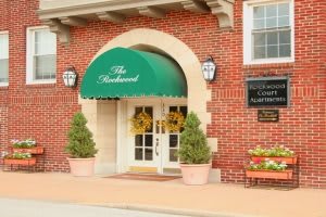 A building entrance with green awning and potted plants.