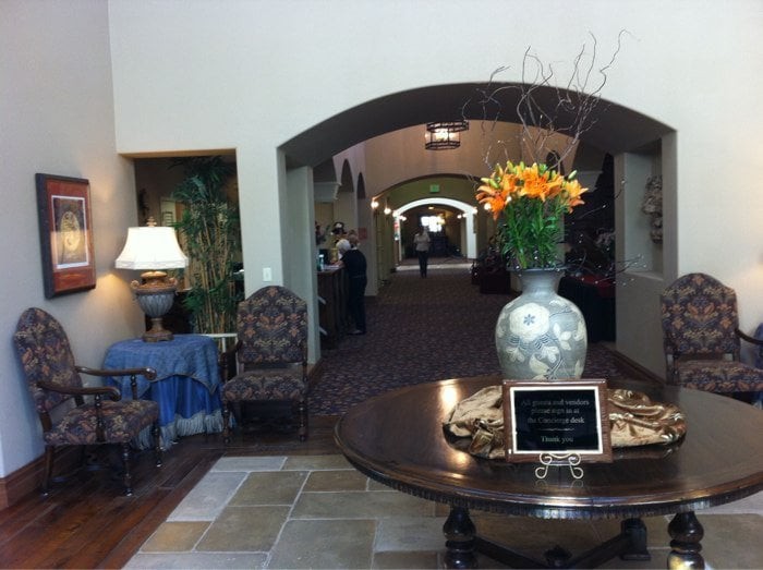A welcoming lobby area featuring a central table with a decorative vase and flowers, leading into a long hallway.