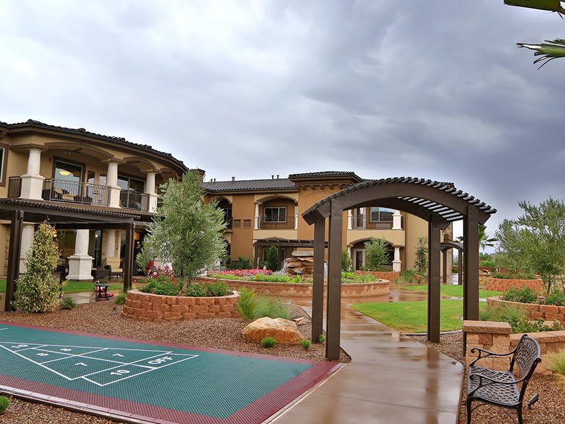 A view of a residential building with a walkway, garden, and stormy sky in the background.