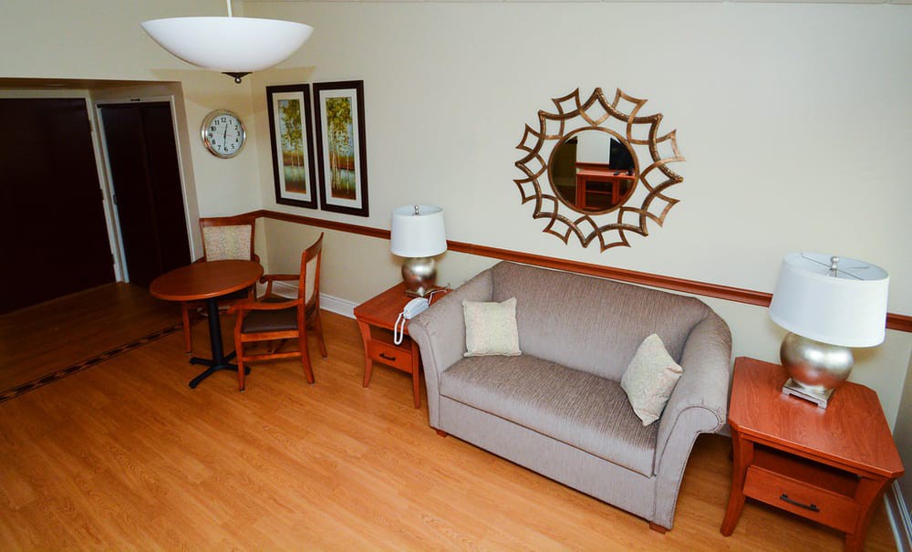 A cozy living room with a sofa, table and chairs, adorned with a decorative mirror and artwork on the walls.