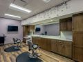 A modern salon interior with stylish chairs and mirrors, featuring wooden cabinets and bright lighting.