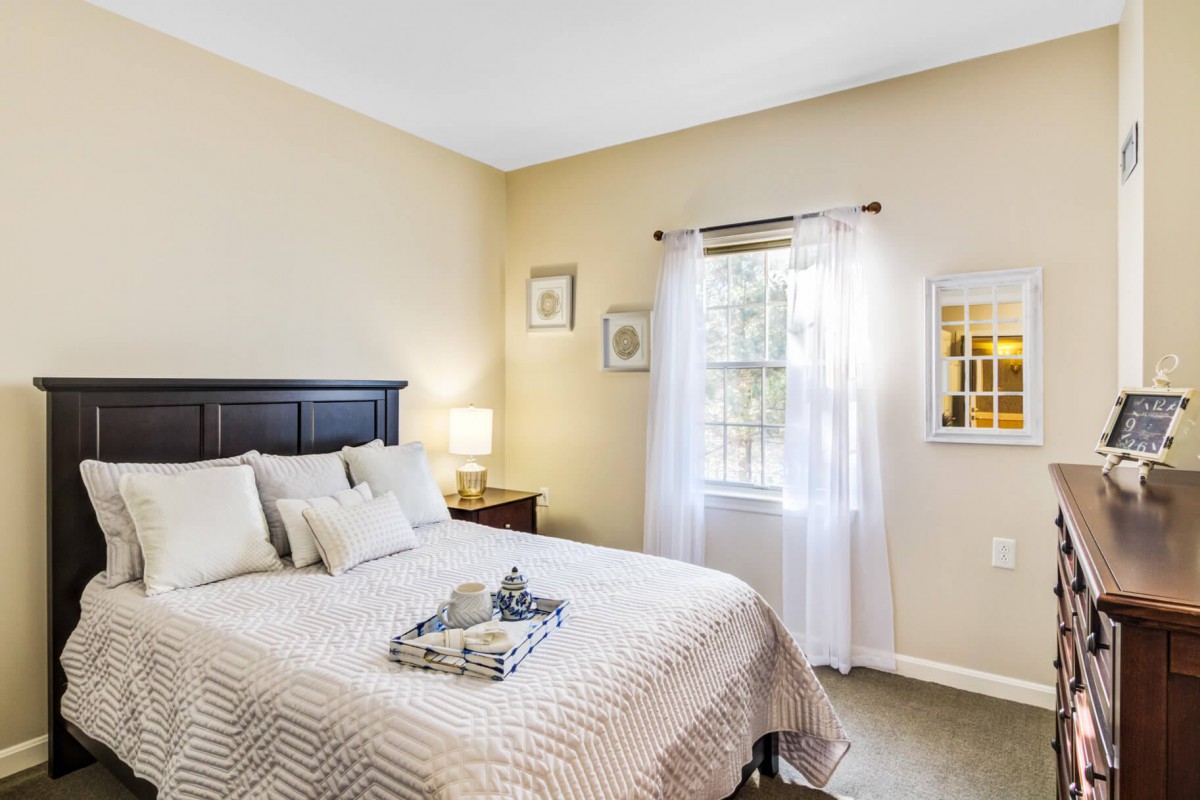 A cozy, well-lit bedroom with a neatly made bed and elegant decor.
