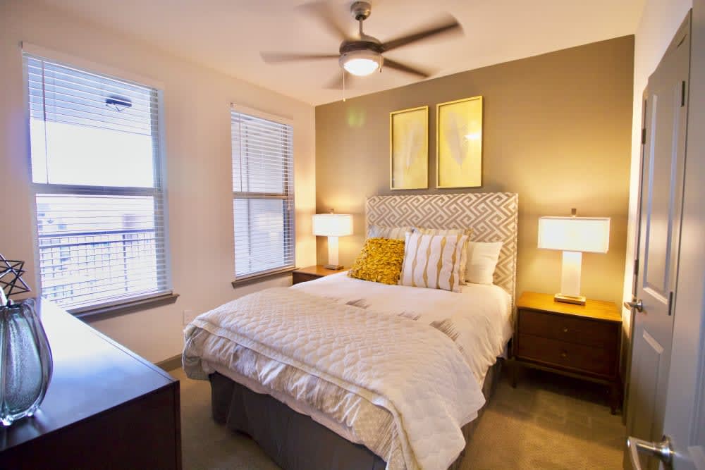A cozy bedroom with a stylish bed, bedside lamps, and a ceiling fan.