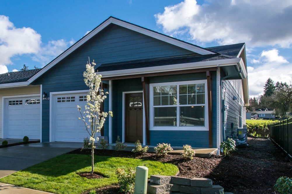 A charming blue house with a landscaped front yard and attached garage.