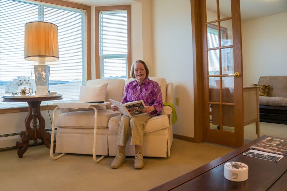 A person sitting on a couch in a cozy living room, reading a book.
