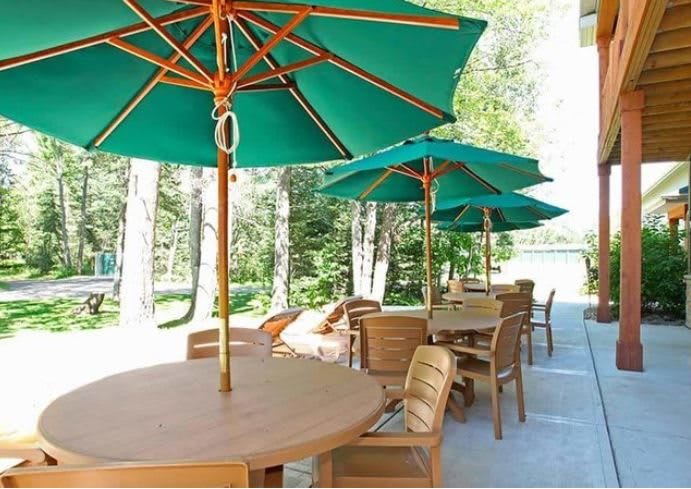 Outdoor patio area with wooden tables and green umbrellas.