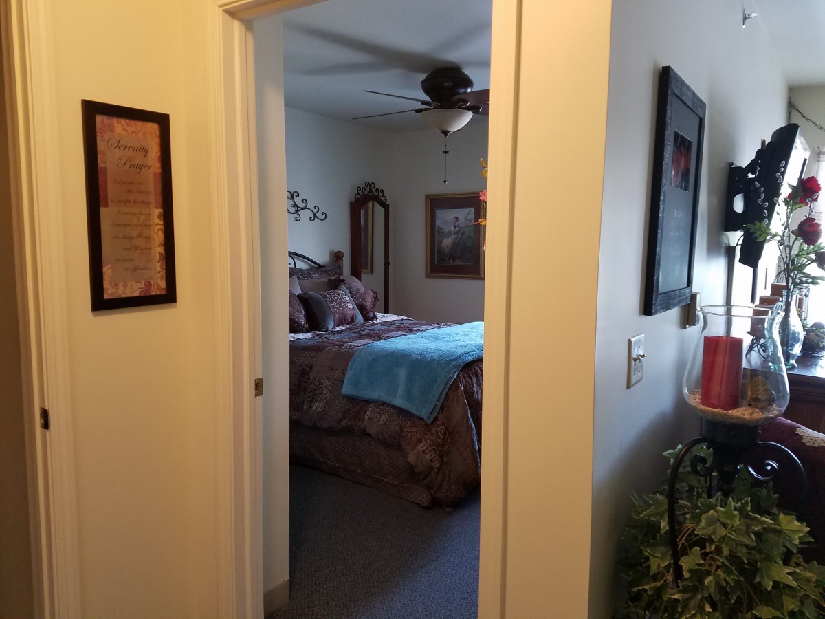 A view into a cozy bedroom through an open doorway, featuring well-arranged furniture and decor.