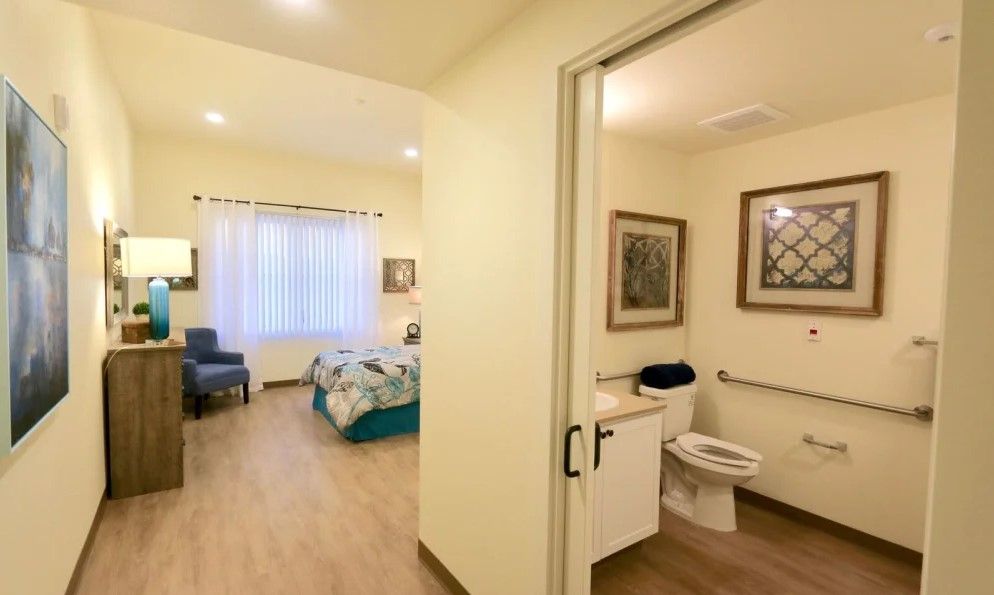 A cozy bedroom connected to an accessible bathroom, featuring simple and modern decor.